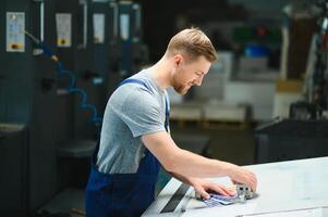 portret van productie lijn arbeider controlerend fabricage werkwijze van modern verpakking industrieel machine in het drukken fabriek foto