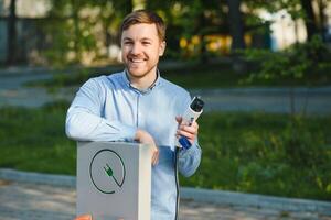 Mens Holding macht opladen kabel voor elektrisch auto. foto