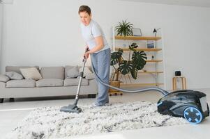 portret van senior vrouw met vacuüm schoonmaakster binnenshuis Bij huis, stofzuigen foto