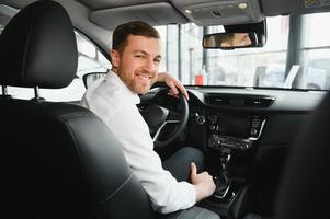 taxi bestuurder glimlachen terwijl draaien over- naar de achterbank op zoek pratend met klanten. geslaagd zakenman man op zoek Bij de achterbank Bij handelaar winkel voordat buying een auto foto