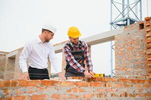 structureel ingenieur en voorman arbeider bespreken, plan werken voor de buitenshuis gebouw bouw plaats foto