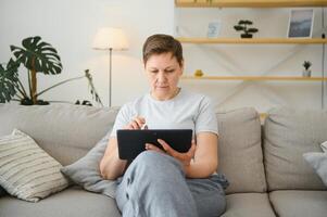 mensen, technologie en internet concept - gelukkig midden- oud vrouw met tablet pc computer Bij huis. foto