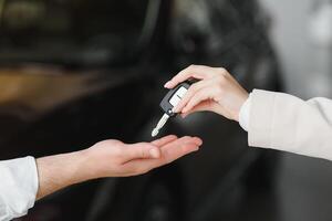 auto uitverkoop. handelaar geven sleutel naar nieuw eigenaar in auto tonen of salon, detailopname foto