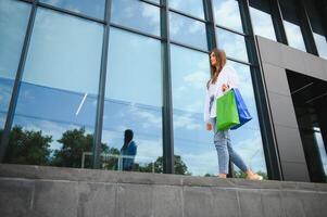 modieus mooi gelukkig vrouw staand met boodschappen doen Tassen in de buurt een boodschappen doen centrum Aan zwart vrijdag. foto