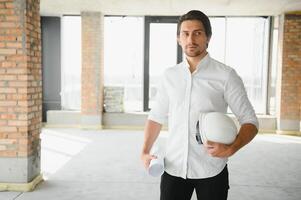 portret van een architect bouwer aan het studeren lay-out plan van de kamers, echt civiel ingenieur werken met documenten Aan bouw plaats, gebouw en huis vernieuwing, professioneel voorman Bij werk. foto