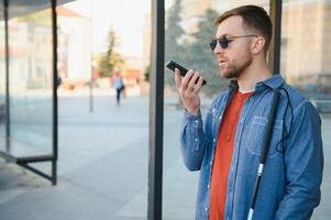 verblind Mens aan het wachten voor bus Bij een bus station foto