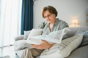 leeftijd en mensen concept - gelukkig senior vrouw lezing krant- Bij huis foto