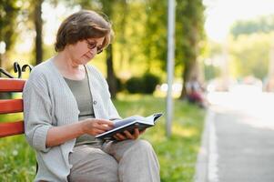 gepensioneerd vrouw lezing een boek Aan de bank foto