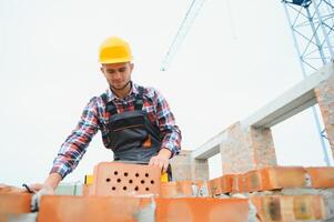 bouw arbeider in uniform en veiligheid uitrusting hebben baan Aan gebouw foto