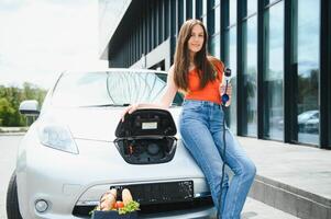 vrouw opladen elektro auto Bij de elektrisch gas- station foto