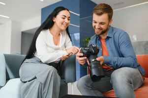 fotograaf in kantoor shows foto model- in camera. consultant past zich aan activiteiten bedrijf net zo geheel. foto sessie medewerkers in werkplek. manager goed uitgevoerd project. foto's het beste medewerkers bedrijf.