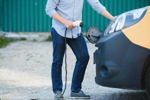 Mens opladen zijn elektrisch auto Bij in rekening brengen station. foto