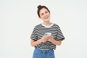 beeld van jong glimlachen vrouw, Holding mobiel telefoon, gebruik makend van smartphone sollicitatie, geïsoleerd over- wit achtergrond foto