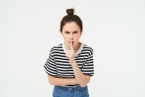 beeld van boos vrouw zwijgend, maakt stil gebaar, druk op vinger naar lippen met gefrustreerd gezicht, houden stil, uitbrander luid persoon, wit achtergrond foto