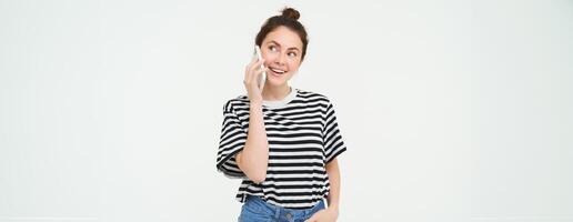 gelukkig jong vrouw praat Aan mobiel telefoon, chats Aan telefoon, toepassingen smartphone, staat over- wit achtergrond foto