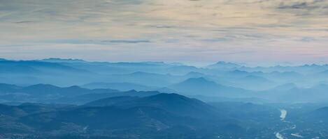 verbazingwekkend dar antenne landschap Bij de Italiaans Alpen in winter en herfst. ochtend- panorama. vallen zonsopkomst Bij de Alpen met vochtigheid en verontreiniging in de lucht. silhouet van de bergen en heuvels foto