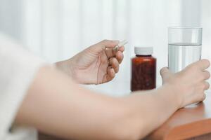 hand- Holding een bril van drinken water met nemen pillen, benadrukkend gezondheidszorg en geneesmiddel foto