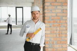 portret van een architect bouwer aan het studeren lay-out plan van de kamers, echt civiel ingenieur werken met documenten Aan bouw plaats, gebouw en huis vernieuwing, professioneel voorman Bij werk. foto