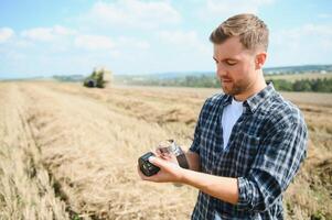 jong boer in tarwe veld- gedurende oogst in zomer foto