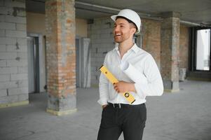 portret van Mens architect Bij gebouw plaats. zelfverzekerd bouw manager vervelend harde hoed. geslaagd volwassen civiel ingenieur Bij bouw plaats met kopiëren ruimte. foto