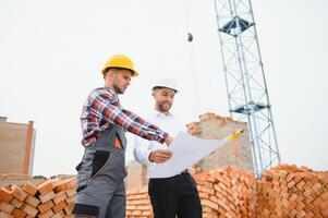 structureel ingenieur en voorman arbeider bespreken, plan werken voor de buitenshuis gebouw bouw plaats foto