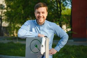 Mens Holding macht opladen kabel voor elektrisch auto. foto