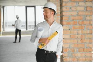 portret van Mens architect Bij gebouw plaats. zelfverzekerd bouw manager vervelend harde hoed. geslaagd volwassen civiel ingenieur Bij bouw plaats met kopiëren ruimte. foto