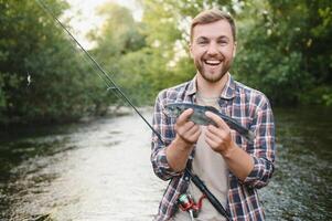 visser vangsten een forel Aan de rivier- in zomer foto