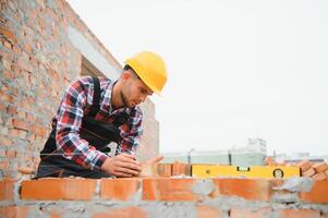 bouw arbeider Mens in werk kleren en een bouw helm. portret van positief mannetje bouwer in harde hoed werken Bij bouw plaats. foto