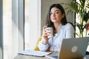 freelance, bedrijf en e-commerce concept. creatief enthousiast vrouw journalist schrijven nieuw artikel, typen Aan laptop, lachend, Schrijf op project ideeën, zitten cafe, drinken koffie werken afgelegen foto