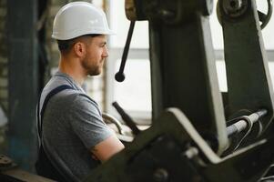 arbeider in beschermend kleding in fabriek gebruik makend van machine foto