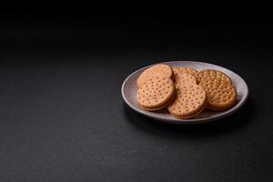 ronde stippel tussendoortje tussendoortje koekjes met room Aan een donker beton achtergrond foto