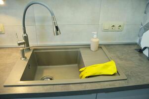 geel huishouden schoonmaak handschoenen liggen Aan de keuken wasbak. foto