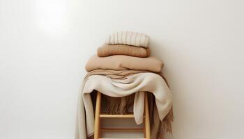 ai gegenereerd stack van warm neutrale beige kleren Aan houten stoel over- wit muur. kasjmier en wol kleding in koel afgezwakt kleuren. Scandinavisch stijl foto