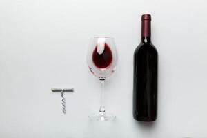 vlak leggen samenstelling met kurketrekker, fles van wijn en elegant glas Aan gekleurde tafel. vlak leggen, top visie wth kopiëren ruimte foto