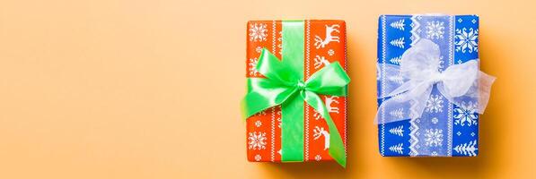 verpakt Kerstmis of andere vakantie handgemaakt Cadeau in papier met wit en groen lint Aan oranje achtergrond. Cadeau doos, decoratie van geschenk Aan gekleurde tafel, top visie foto