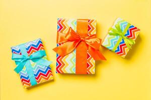 geschenk doos met blauw, groen en oranje boog voor Kerstmis of nieuw jaar dag Aan geel achtergrond, top visie foto
