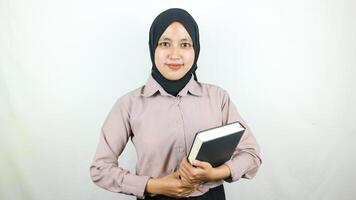 glimlachen jong Aziatisch moslim leerling Holding boek, op zoek Bij camera geïsoleerd Aan wit achtergrond. foto