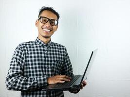 portret van een Aziatisch Mens Holding een laptop met een glimlachen gezicht uitdrukking. reclame concept. foto