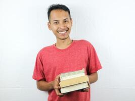 portret van een Aziatisch Mens glimlachen en Holding stack van boeken, geïsoleerd Aan wit achtergrond. foto