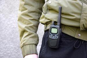 de walkietalkie is vastgemaakt naar de riem van de man's broek. foto