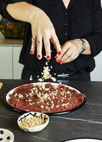 gastvrouw maken carpaccio in huis keuken met vers ingrediënten Aan zwart marmeren foto
