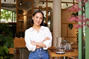 portret van glimlachen Aziatisch meisje in wit halsband shirt, werken in cafe, beheren restaurant, op zoek zelfverzekerd en elegant foto