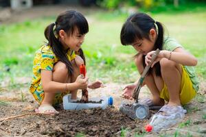 weinig meisje aanplant planten in potten van gerecycled water flessen in de achtertuin. recycle water fles pot, tuinieren activiteiten voor kinderen. recycling van plastic verspilling foto