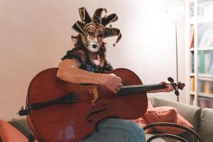 aantrekkelijk vrouw vervelend een masker is spelen een cello foto