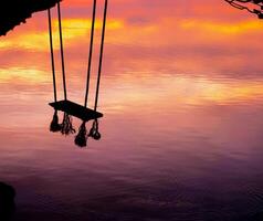 hout schommel mooi zonsondergang Aan de zee met roze lucht achtergrond foto