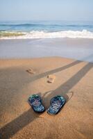 blauw strand slippers Aan een zanderig strand. voetafdrukken van een Mens Aan de oever. rust uit door de zee, zomer avonturen. surfen lawaai en zee schuim foto