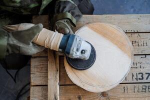 de werkwijze van creëren gereedschap van hout. de meester bezuinigingen een cirkel van hout, een kader van bovenstaande. Aan de handen van speciaal handschoenen en uniform camouflage afdrukken. hout verwerken en creatie van speelgoed foto