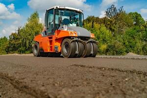 weg rol werken Aan de nieuw weg bouw plaats. houdende een nieuw asfalt Aan de weg. bouw van de weg foto