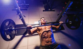 atletische man in sportschool oefenen op de barbell bankdrukken. foto